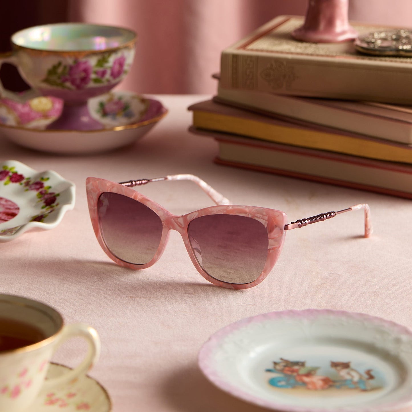 lifestyle - tea set with harry potter x diff eyewear featuring professor umbridge cat eye sunglasses with a pink mother of pearl frame and wine gradient lenses front view