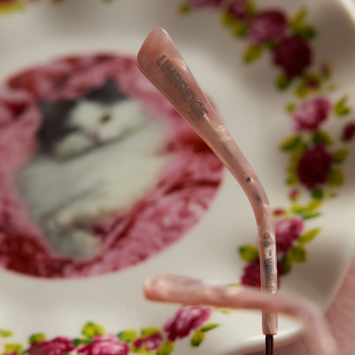 lifestyle - harry potter x diff eyewear featuring professor umbridge cat eye sunglasses with a pink mother of pearl frame and wine gradient lenses detailed temple tip view