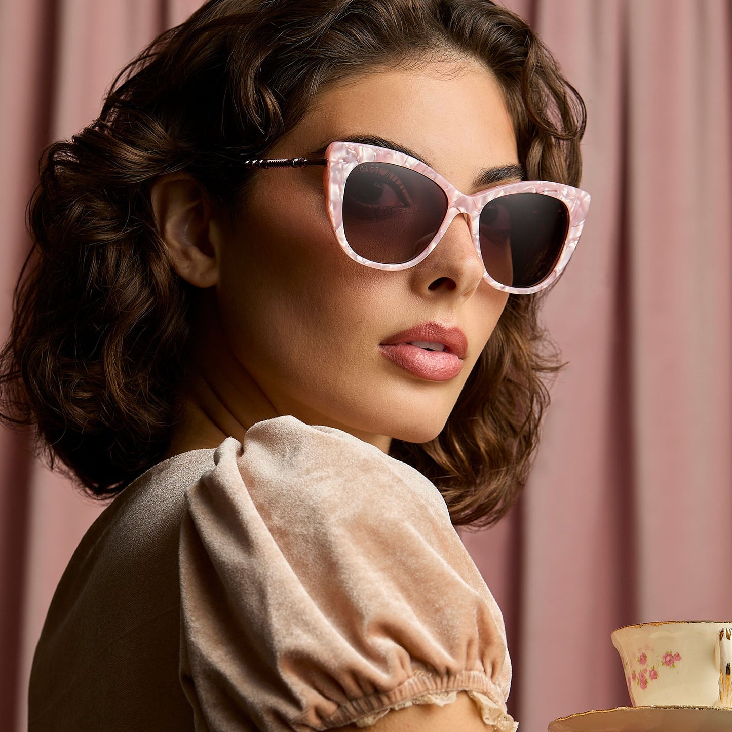 lifestyle - female wearing harry potter x diff eyewear featuring professor umbridge cat eye sunglasses with a pink mother of pearl frame and wine gradient lenses side view