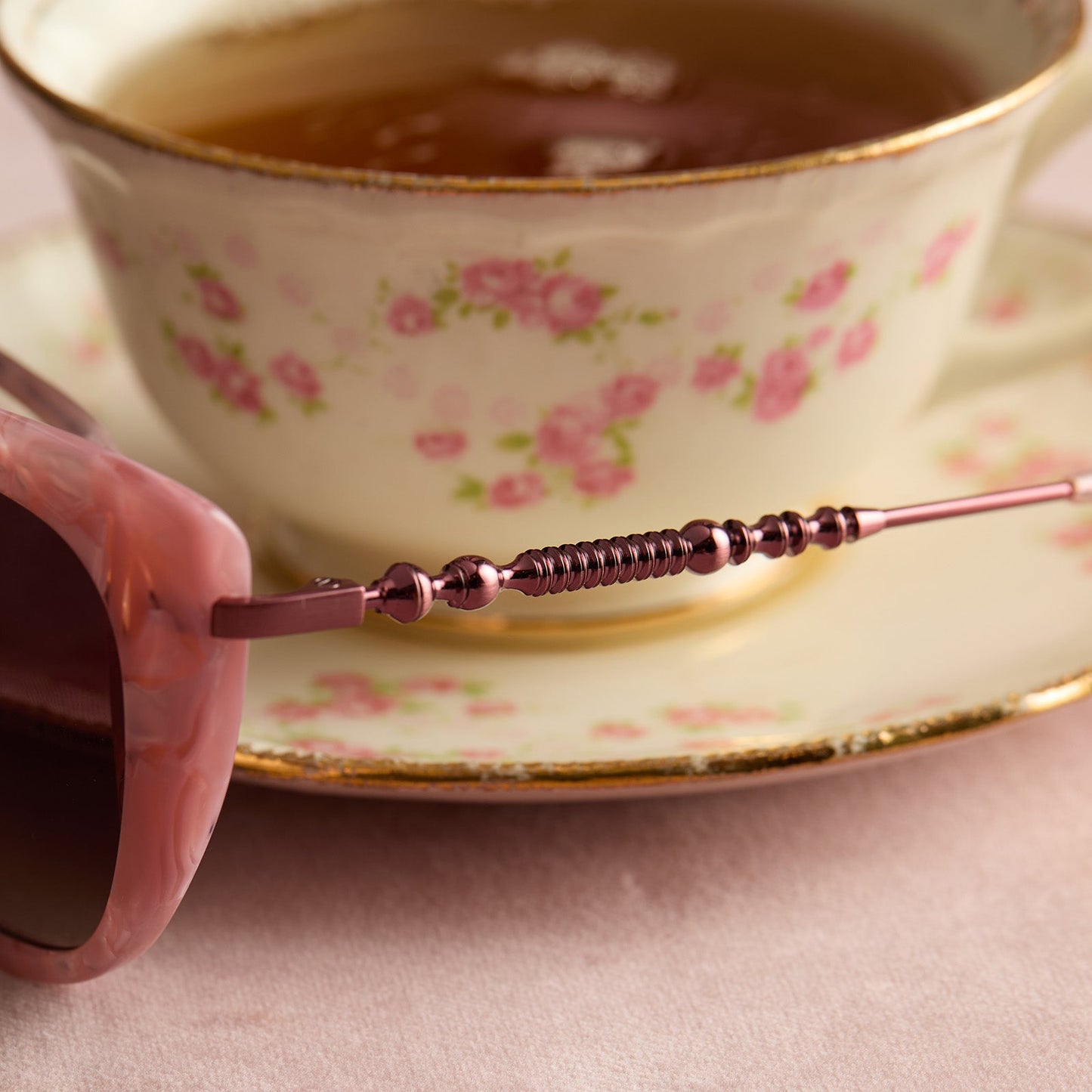 lifestyle - harry potter x diff eyewear featuring professor umbridge cat eye sunglasses with a pink mother of pearl frame and wine gradient lenses detailed temple view with tea cup