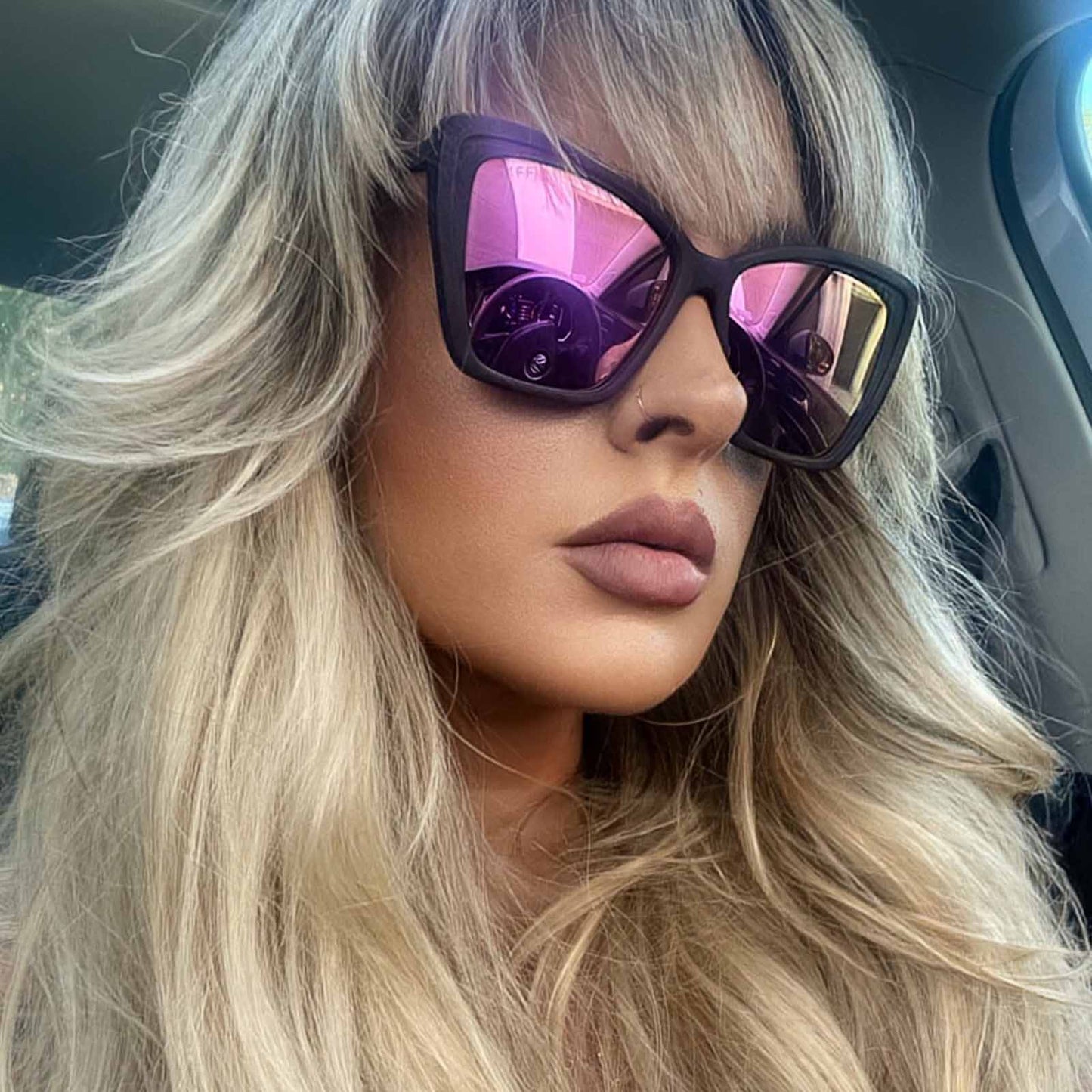 lifestyle - blonde female wearing the diff eyewear becky ii cat eye sunglasses with a matte black frame and pink mirror polarized lenses