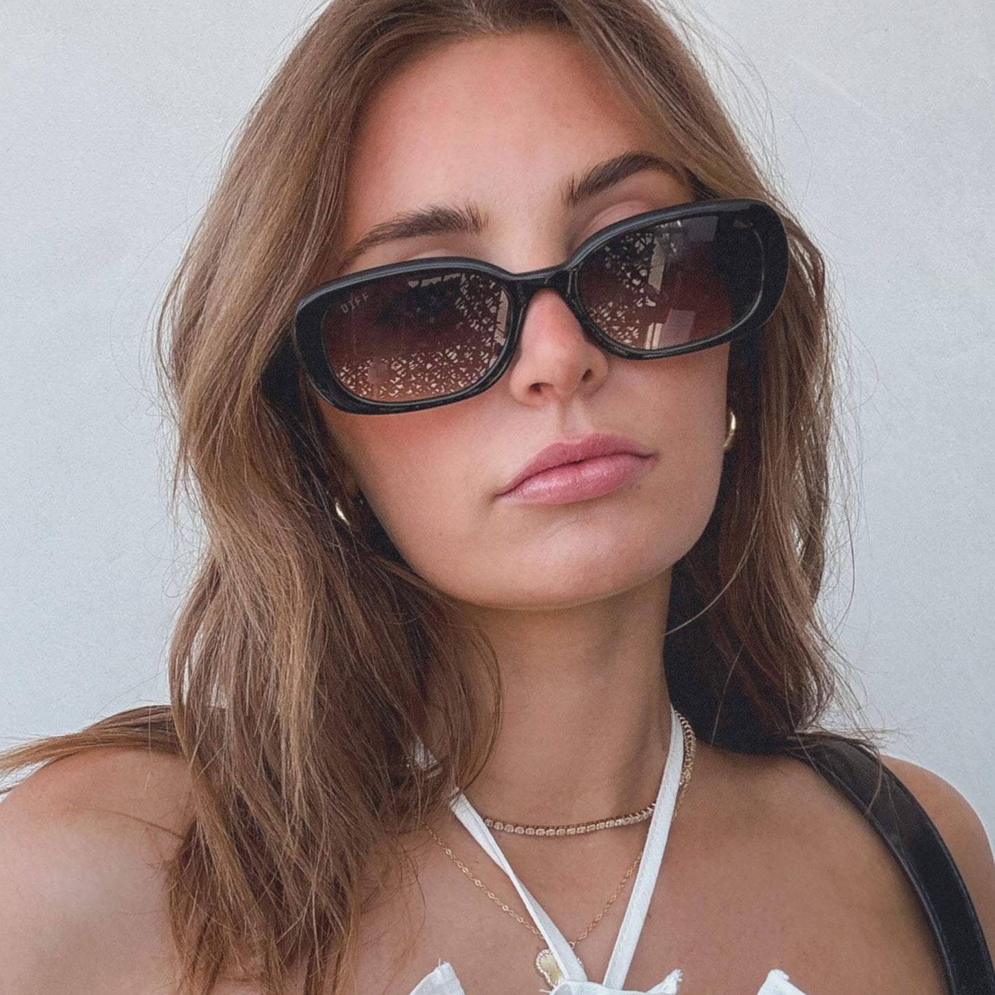 lifestyle - aspyn ovard x diff eyewear female wearing the cove oval sunglasses with a black frame and grey gradient lenses front view