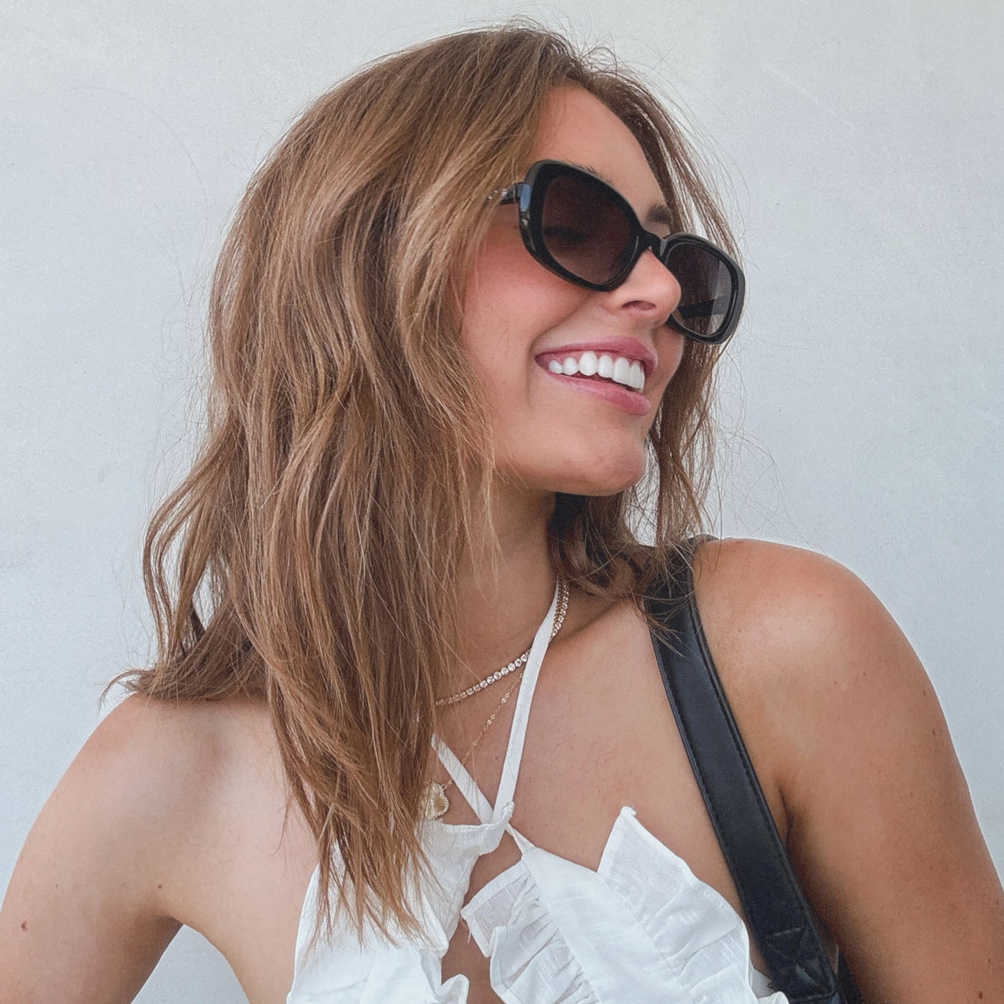 lifestyle - aspyn ovard x diff eyewear female wearing the cove oval sunglasses with a black frame and grey gradient lenses angled view