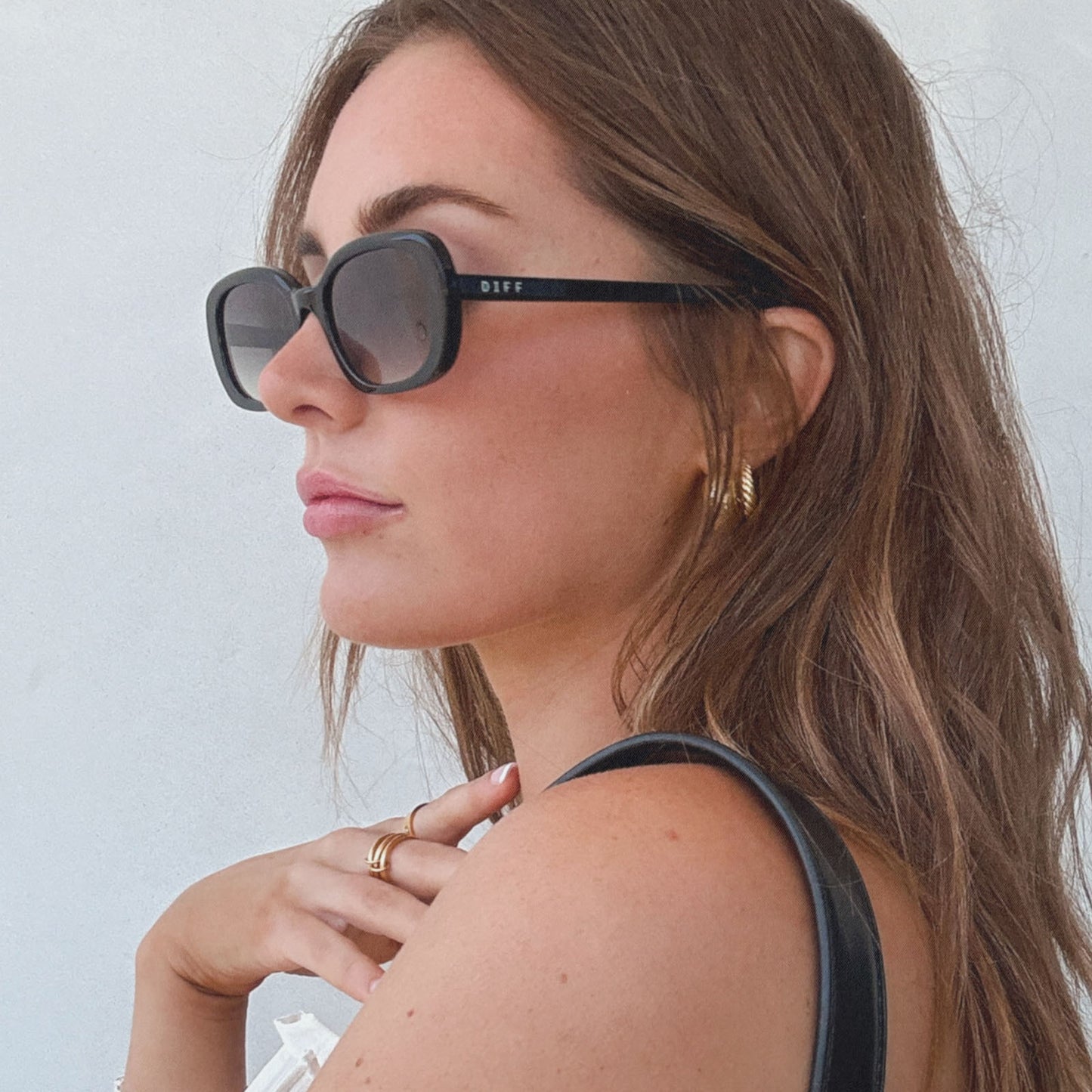 lifestyle - aspyn ovard x diff eyewear female wearing the cove oval sunglasses with a black frame and grey gradient lenses side view