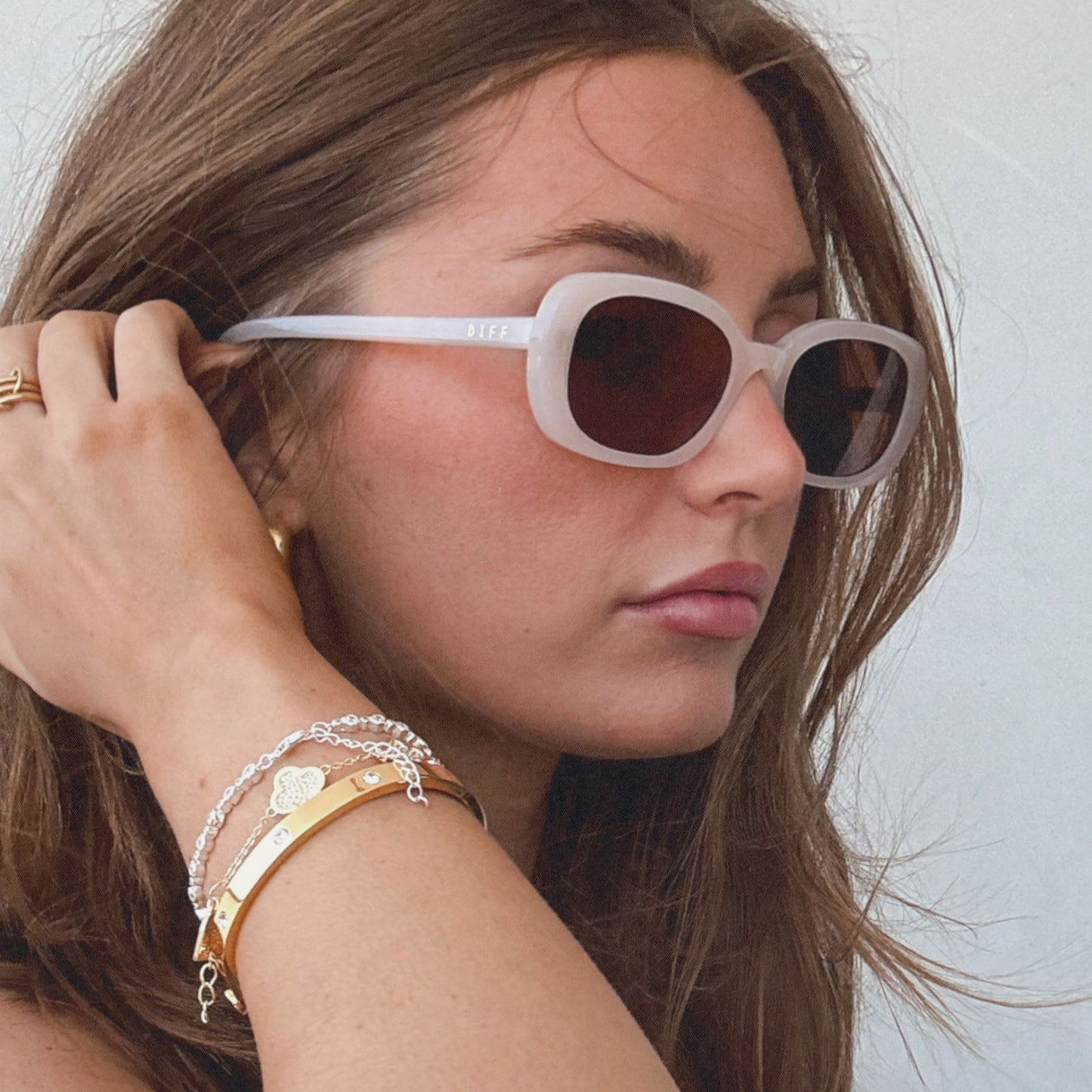 lifestyle - aspyn ovard x diff eyewear female wearing the cove oval sunglasses with a milky blush frame and brown lenses side view