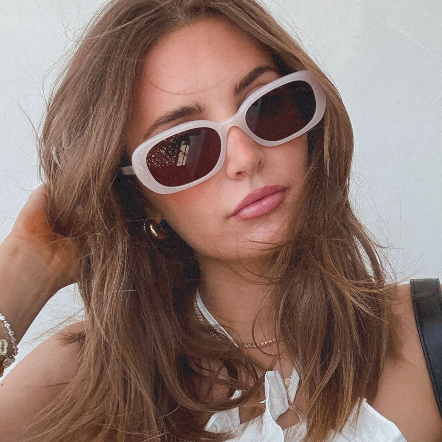 lifestyle - aspyn ovard x diff eyewear female wearing the cove oval sunglasses with a milky blush frame and brown lenses front view