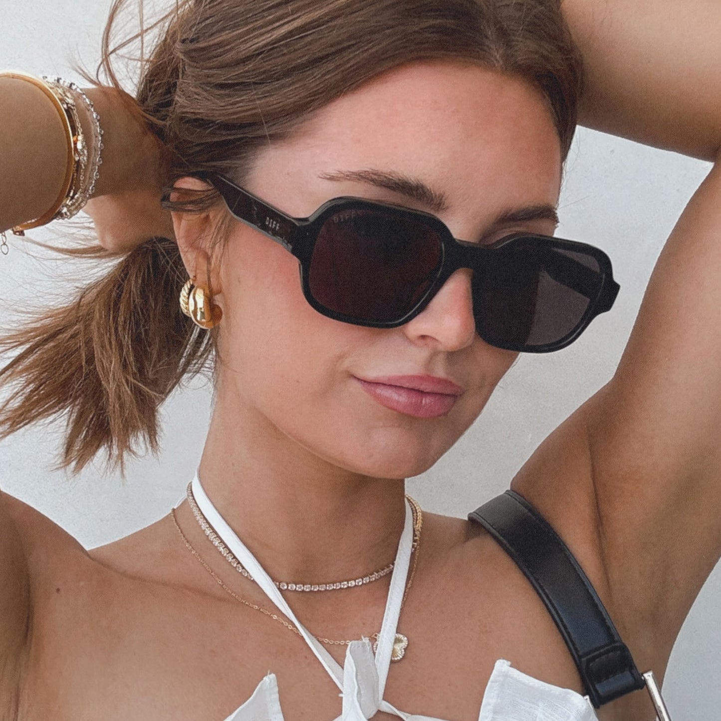 lifestyle - aspyn ovard x diff eyewear female wearing the lola square sunglasses with a black frame and grey lenses angled view