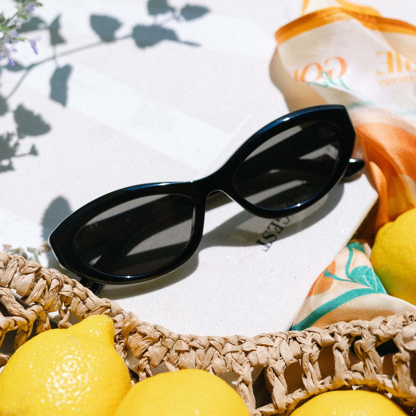 flat lay of jessie james decker x diff eyewear featuring the dolce bella oval sunglasses with a black frame and grey lenses top view