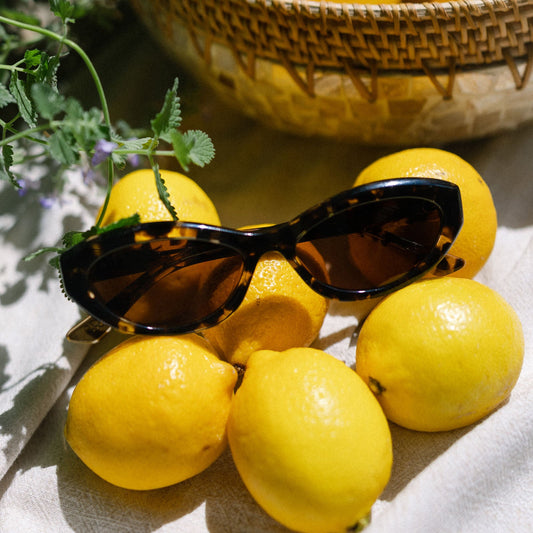 flat lay of jessie james decker x diff eyewear featuring the dolce bella oval sunglasses with a espresso tortoise frame and brown lenses top view