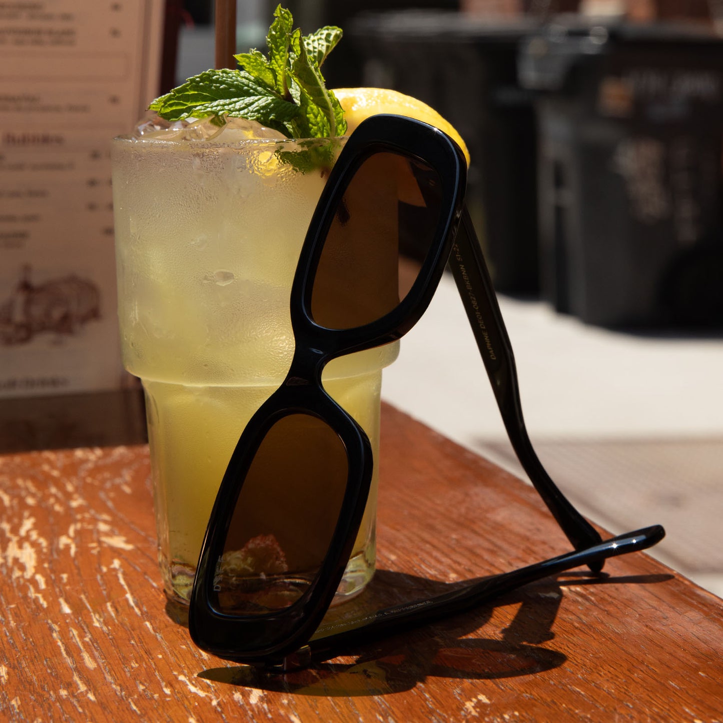 still life of diff eyewear daphne rectangle sunglasses with a black with silver metal frame and brown lenses front view