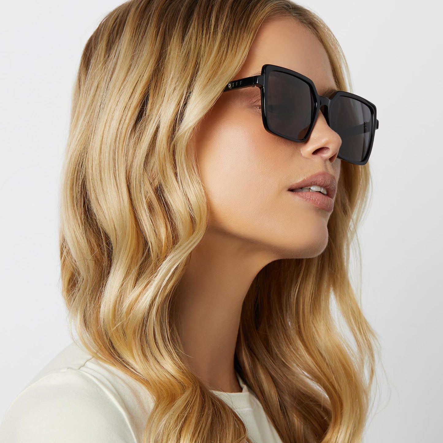 on model - blonde female wearing diff eyewear featuring the esme square sunglasses with a black frame and grey polarized lenses angled view