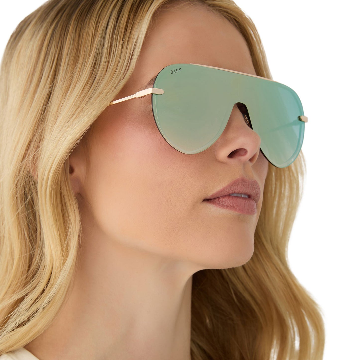 on model - female wearing diff eyewear featuring the imani shield sunglasses with a gold frame and cool matcha green mirror lenses angled view