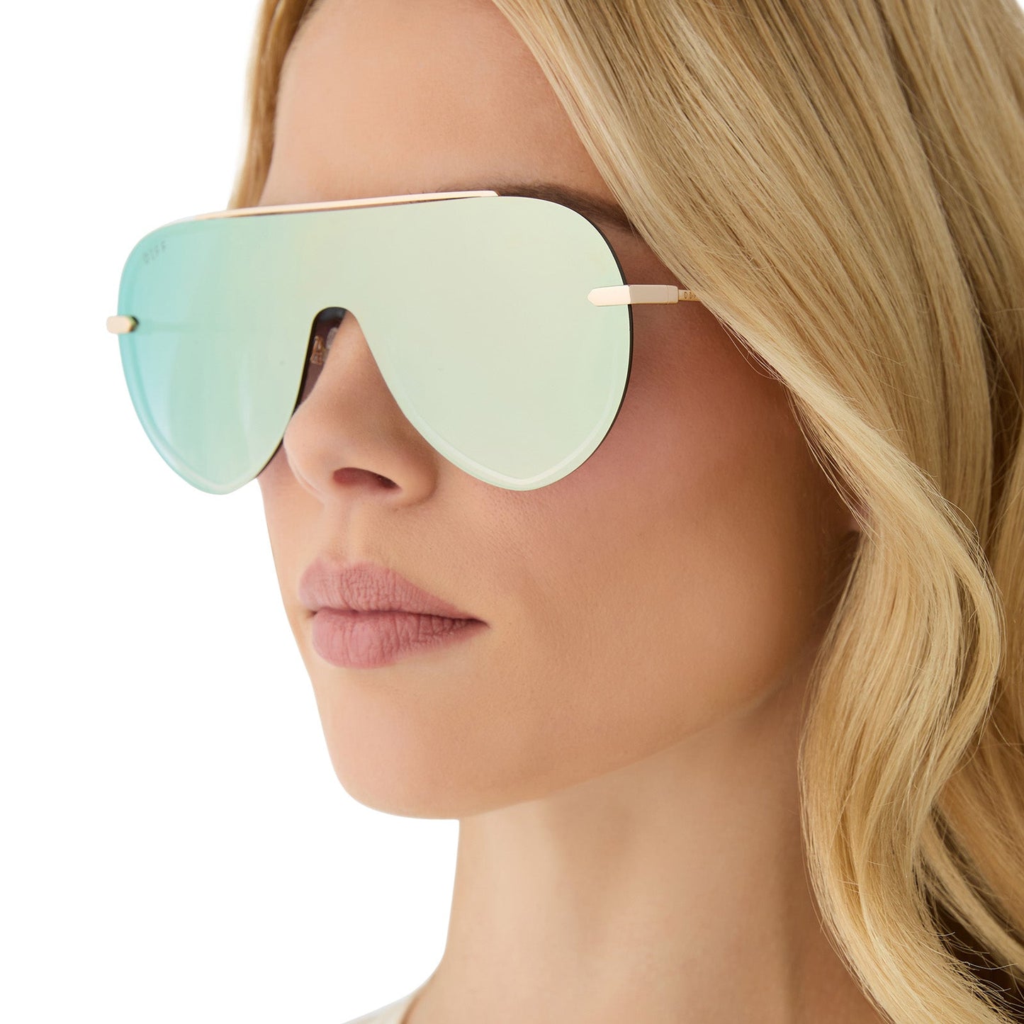 on model - female wearing diff eyewear featuring the imani shield sunglasses with a gold frame and cool matcha green mirror lenses side view