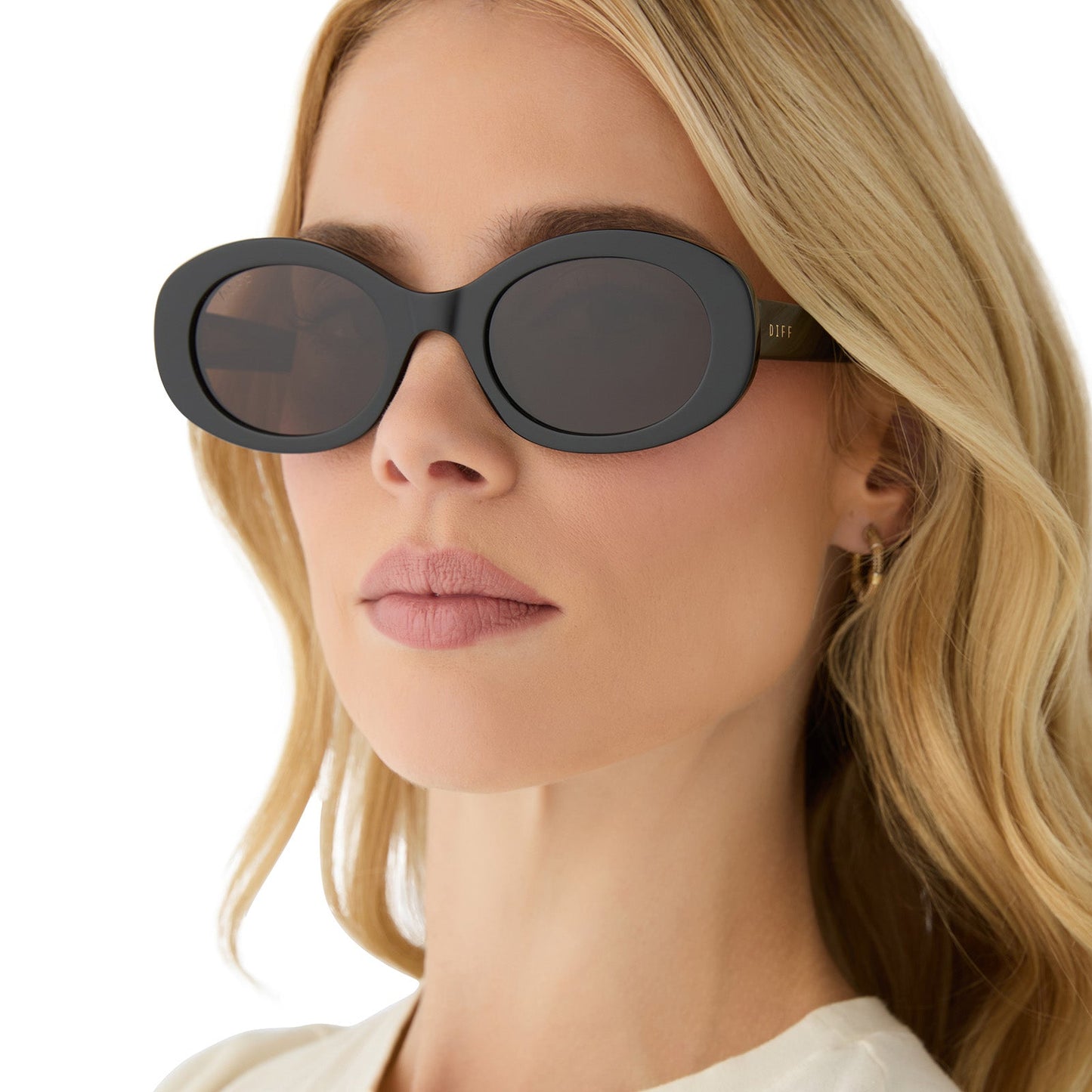 on model - female wearing diff eyewear featuring the lainey oval sunglasses with a black frame and brown polarized lenses angled view