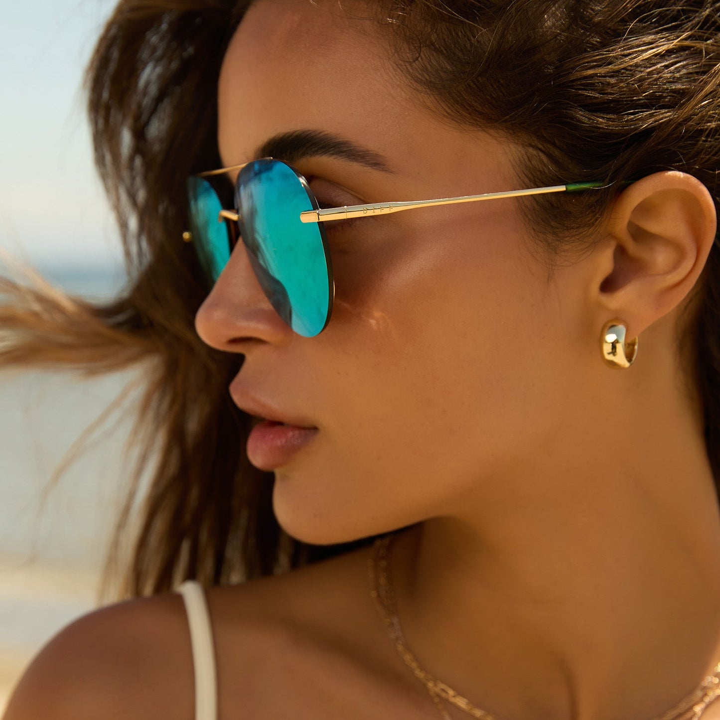 lifestyle - female while at the beach wearing diff eyewear lenox aviator sunglasses with a gold metal frame, green temple tips and green mirror polarized lenses side view