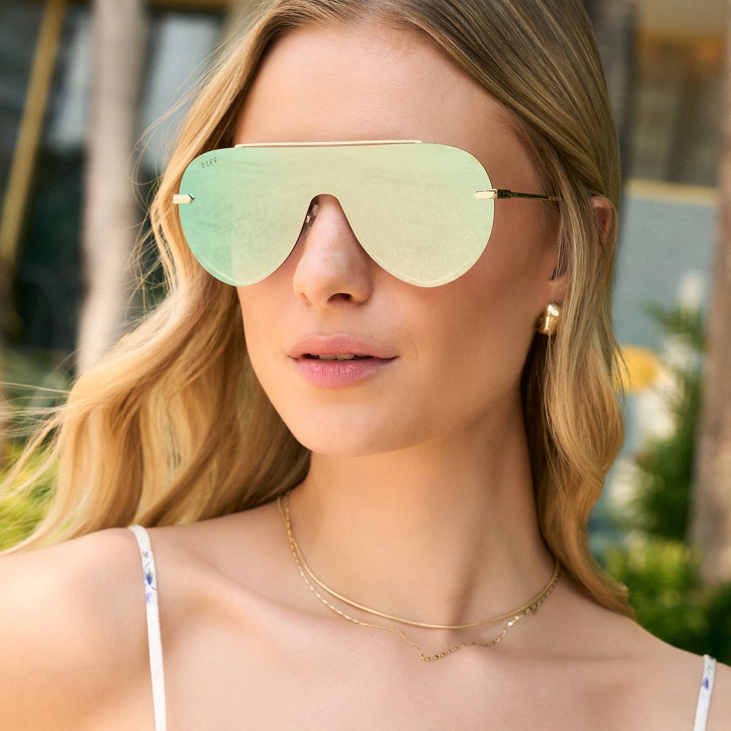 on model - female wearing diff eyewear featuring the imani shield sunglasses with a gold frame and cool matcha green mirror lenses front view