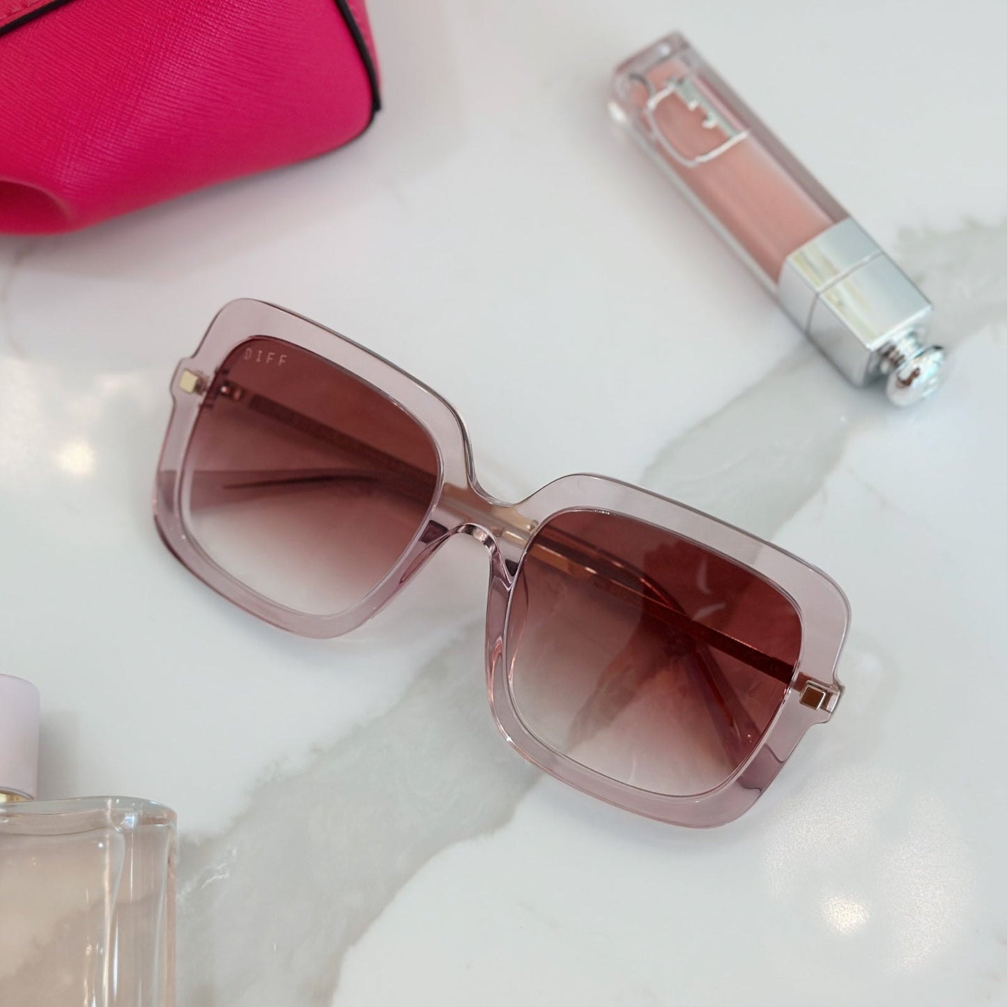 lifestyle - layout of diff eyewear sandra square sunglasses with a light pink crystal frame and peach dusk gradient lenses