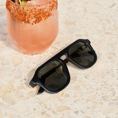 still life - jena sims x diff eyewear the sims navigator sunglasses laying on a table with a drink