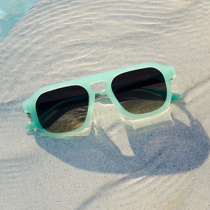 still life - jena sims x diff eyewear the sims navigator sunglasses with a bronco blue with silver metal frame and grey gradient polarized lenses laying by the pool