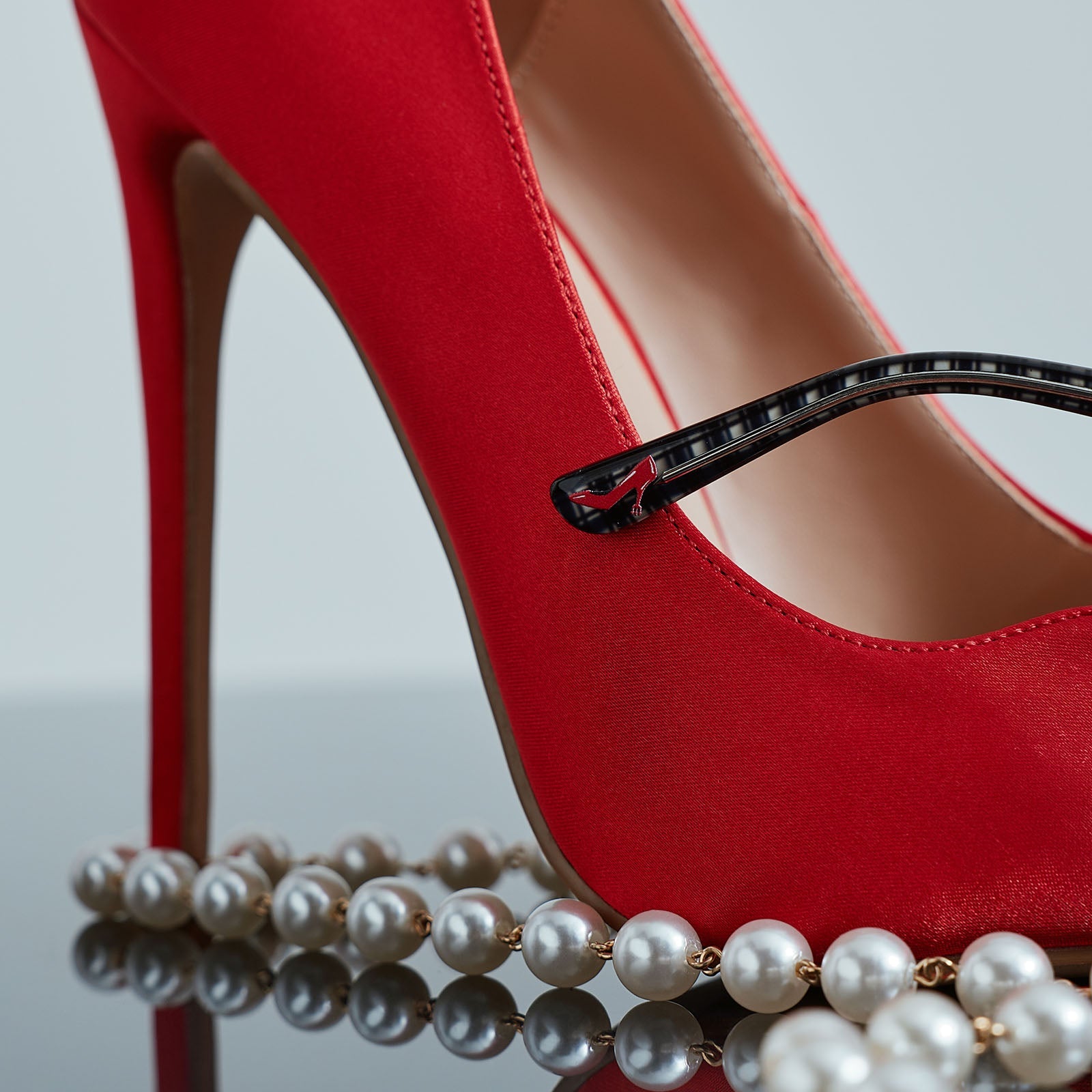 still life of devil wears prada red stiletto shoe with diff eyewear pearl chain