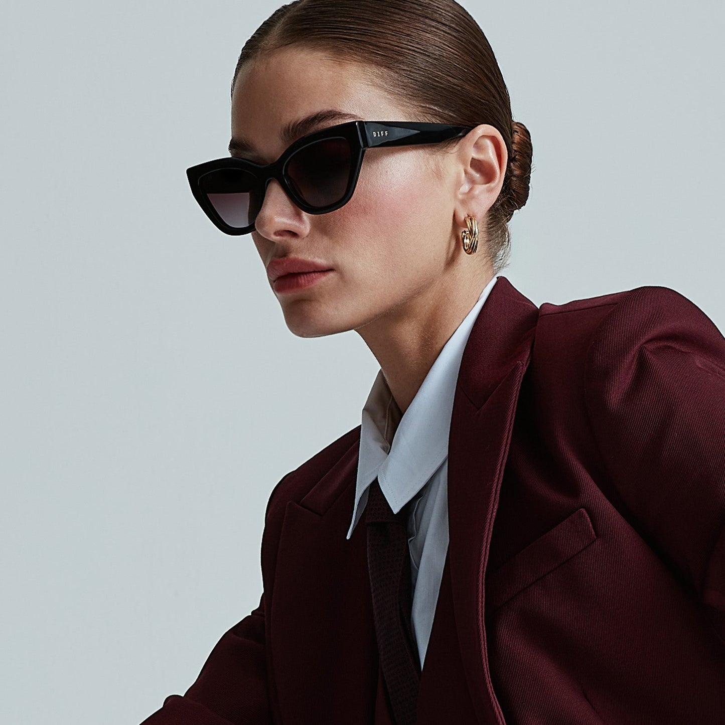 on model - female seated wearing devil wears prada x diff eyewear emily black acetate sunglasses