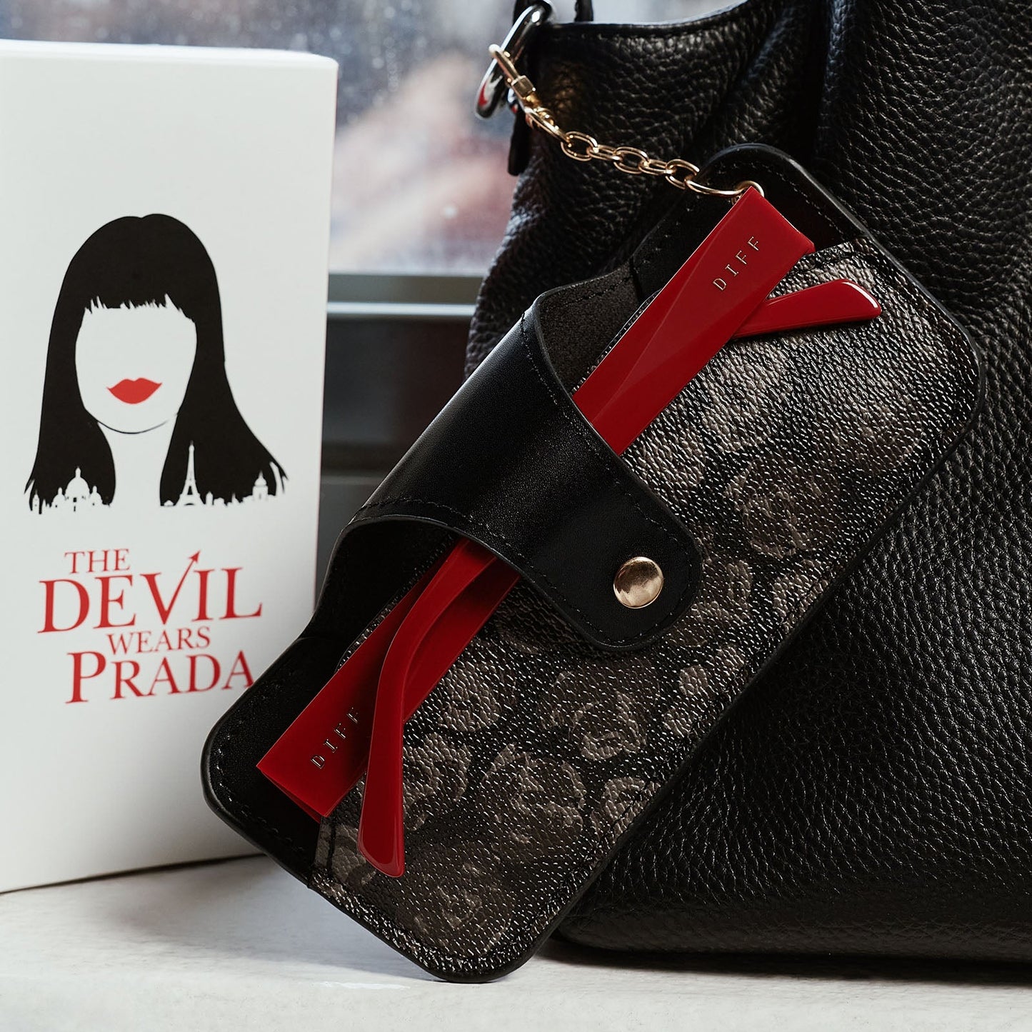 still life - the devil wears prada x diff eyewear emily sunglasses stored in carrying case attached to purse.