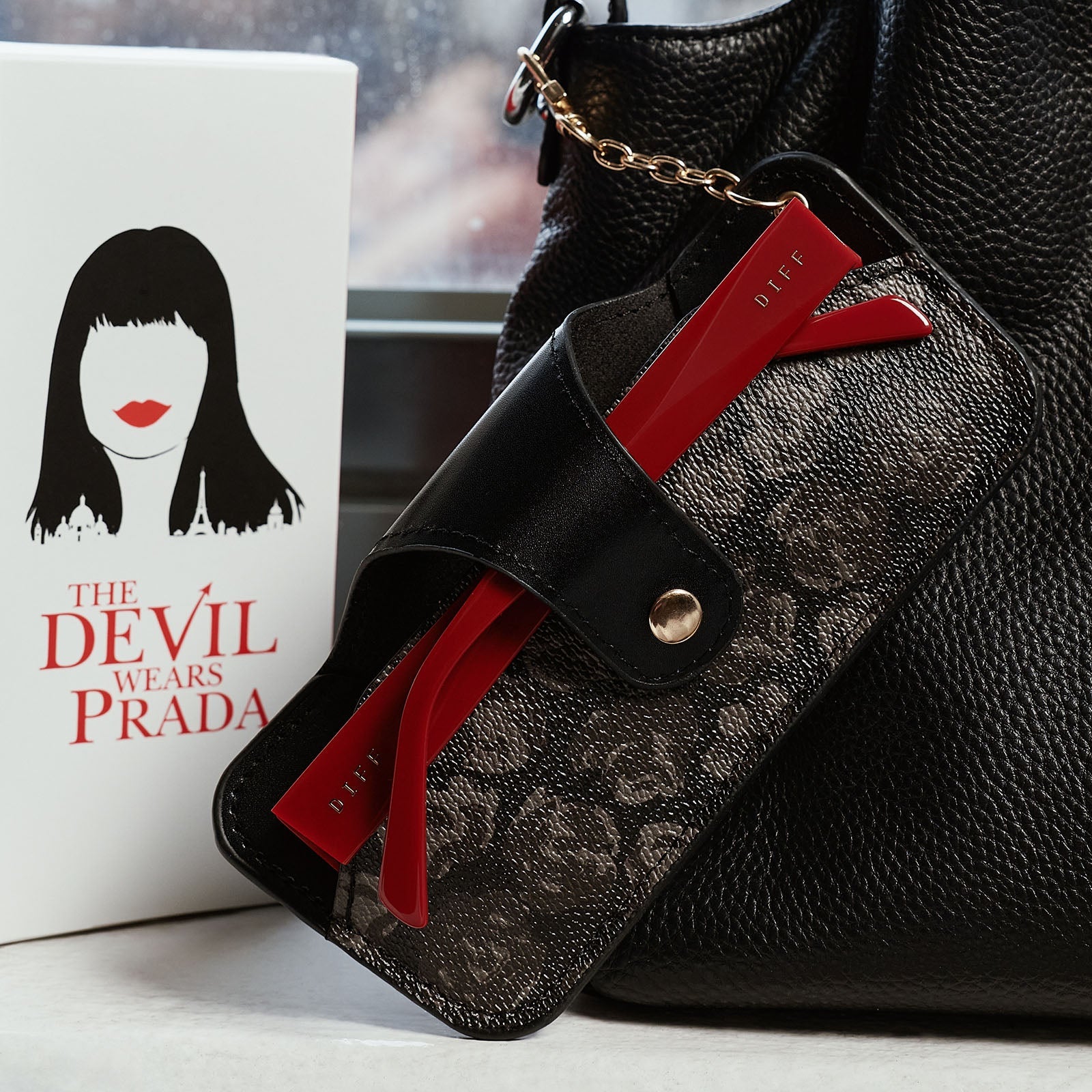 still life - the devil wears prada x diff eyewear emily sunglasses stored in carrying case attached to purse.