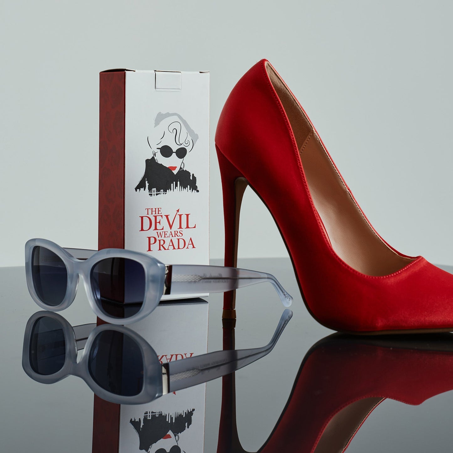 still life - the devil wears prada x diff eyewear of mirana silver sunglasses next to a red stiletto shoe
