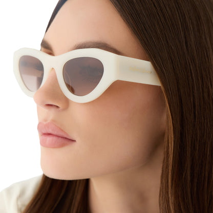 on model - female wearing for love and lemons x diff eyewear featuring the lucy cat eye sunglasses with a meringue cream frame and brown gradient lenses angled view