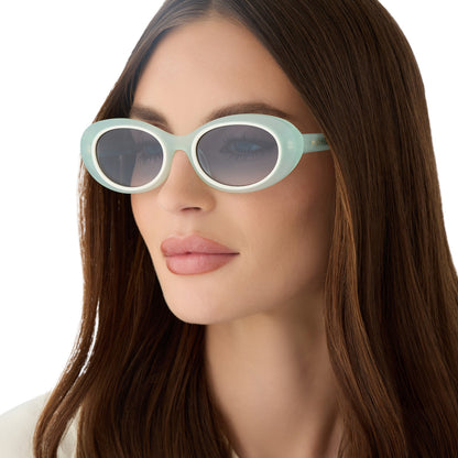 on model - female wearing for love and lemons x diff eyewear featuring the sabrina oval sunglasses with a pastel sage frame and blue gradient lenses angled view