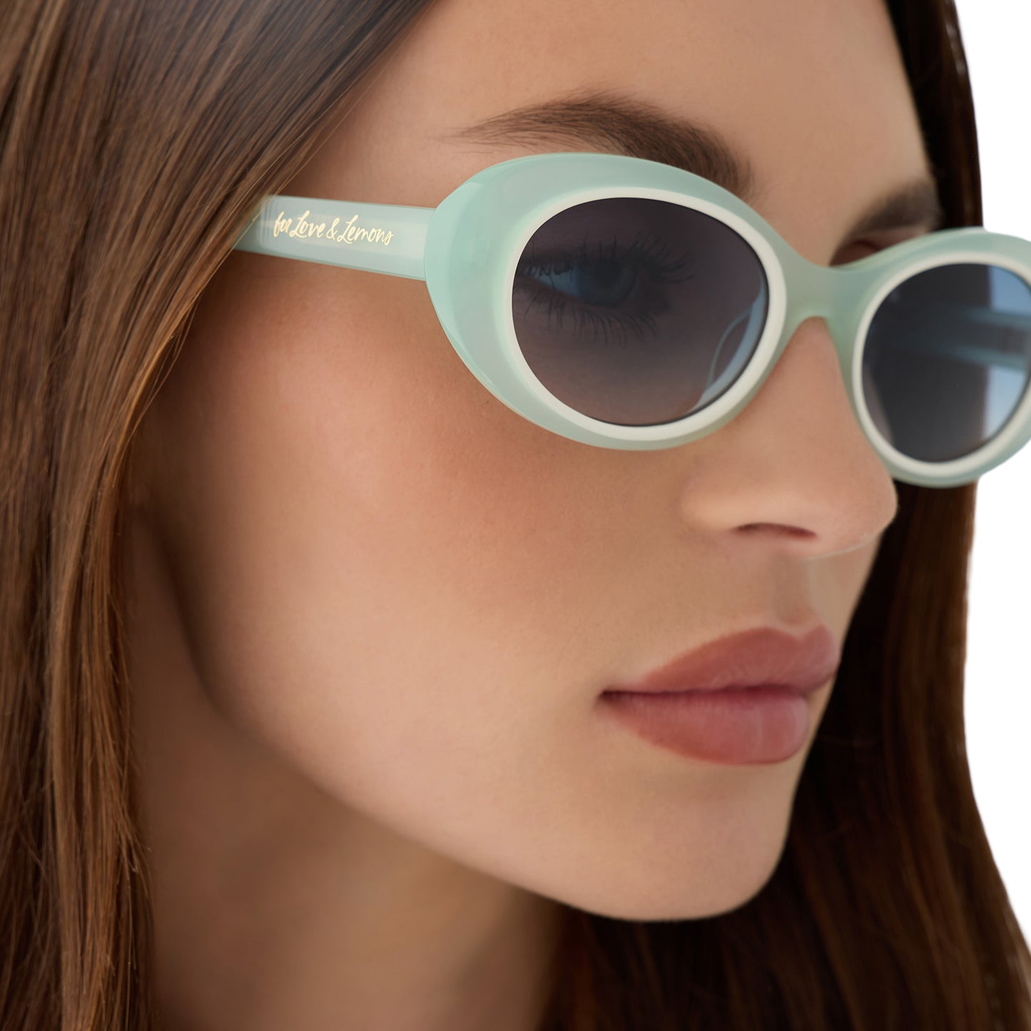 on model - female wearing for love and lemons x diff eyewear featuring the sabrina oval sunglasses with a pastel sage frame and blue gradient lenses detailed view