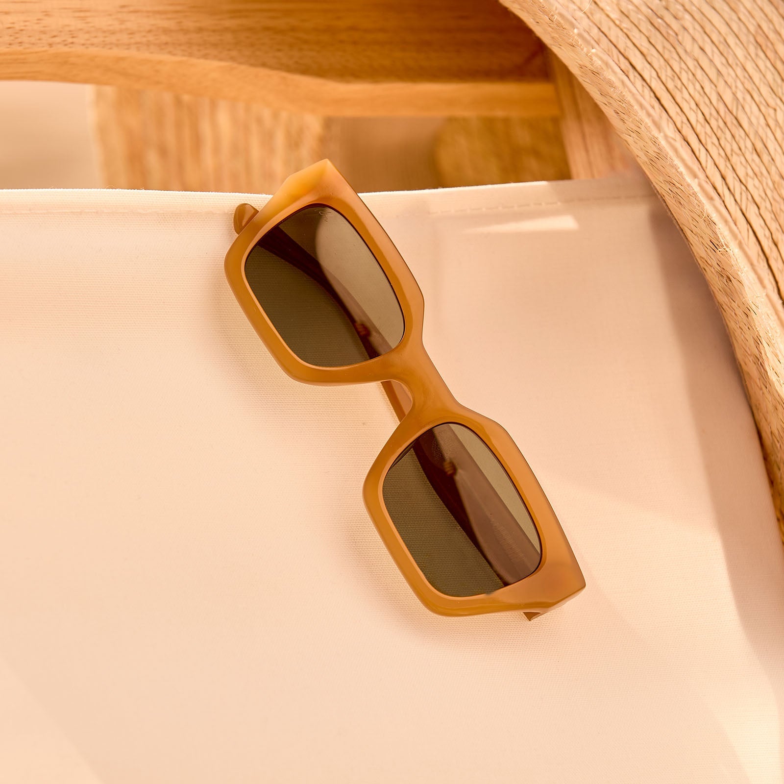 still life - travis mathews x diff eyewear the solana cat eye sunglasses with a caramel acetate frame and g15 polarized lenses left on a chair