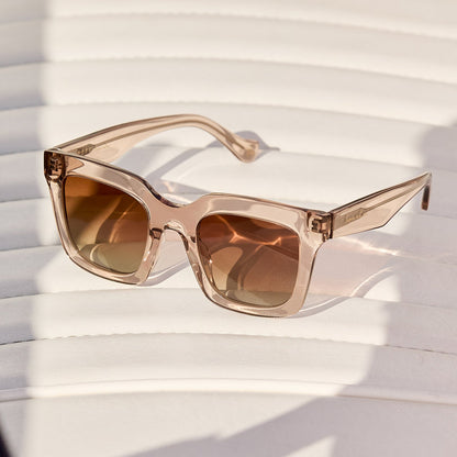 still life - laying on a chair is travis mathews x diff eyewear the valencia square sunglasses with a soft taupe crystal acetate frame and brown gradient polarized lenses angled view