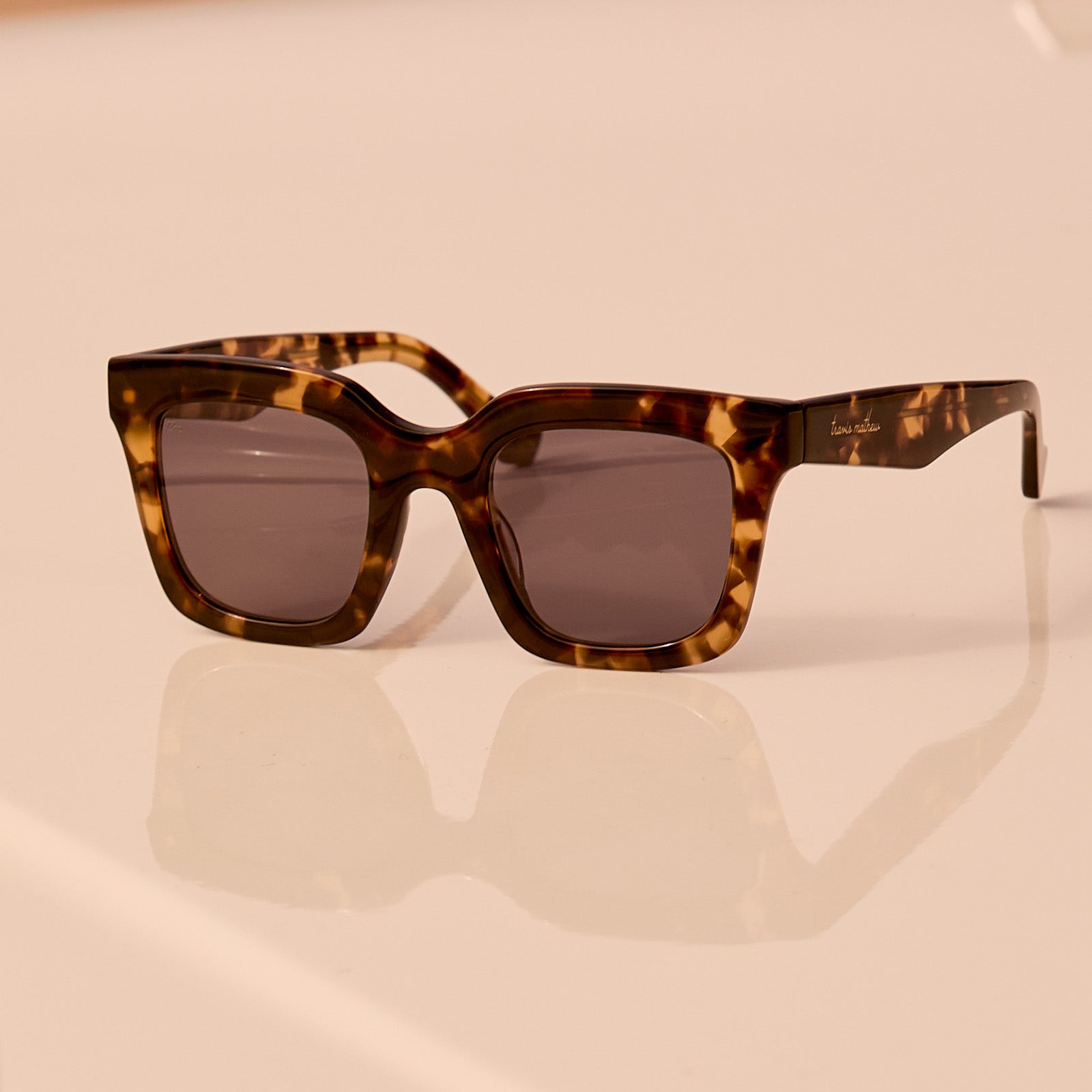 still life - travis mathews x diff eyewear the valencia square sunglasses with a tortoise acetate frame and grey polarized lenses angled view laying on a car