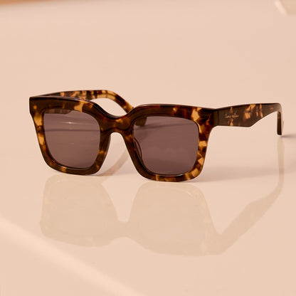 still life - travis mathews x diff eyewear the valencia square sunglasses with a tortoise acetate frame and grey polarized lenses angled view laying on a car