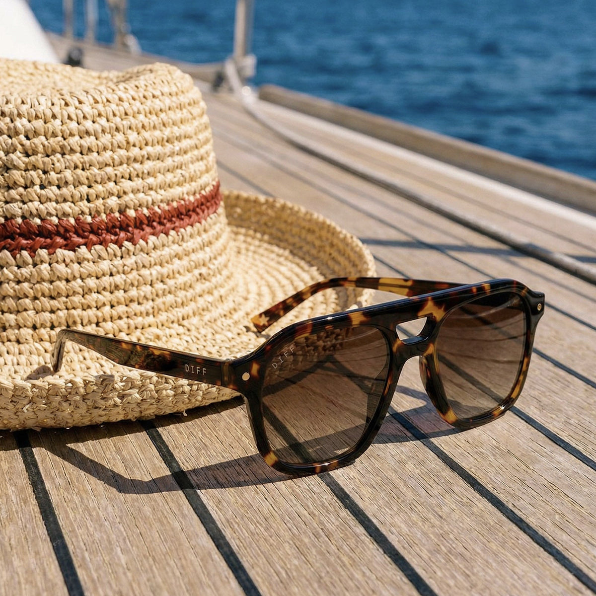 still life -  beach riot x diff eyewear the coast navigator sunglasses with a tortoise acetate frame and brown gradient lenses laying on a deck of a boat