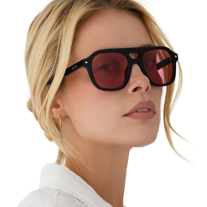 on model - female wearing beach riot x diff eyewear the coast navigator sunglasses with a black acetate frame and red tinted lenses angled view