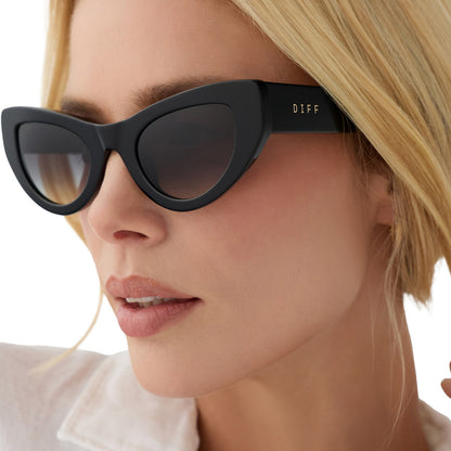 on model - female wearing beach riot x diff eyewear the mesa cat eye sunglasses with a black acetate frame and grey gradient lenses angled view