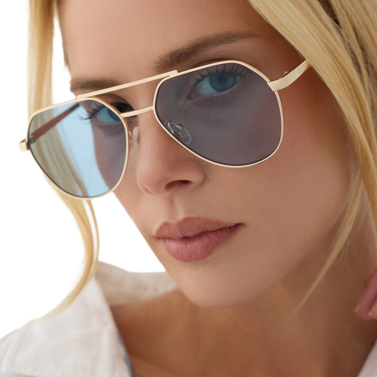 on model - female wearing beach riot x diff eyewear the reserve aviator sunglasses with a gold metal frame and blue tint lenses angled view
