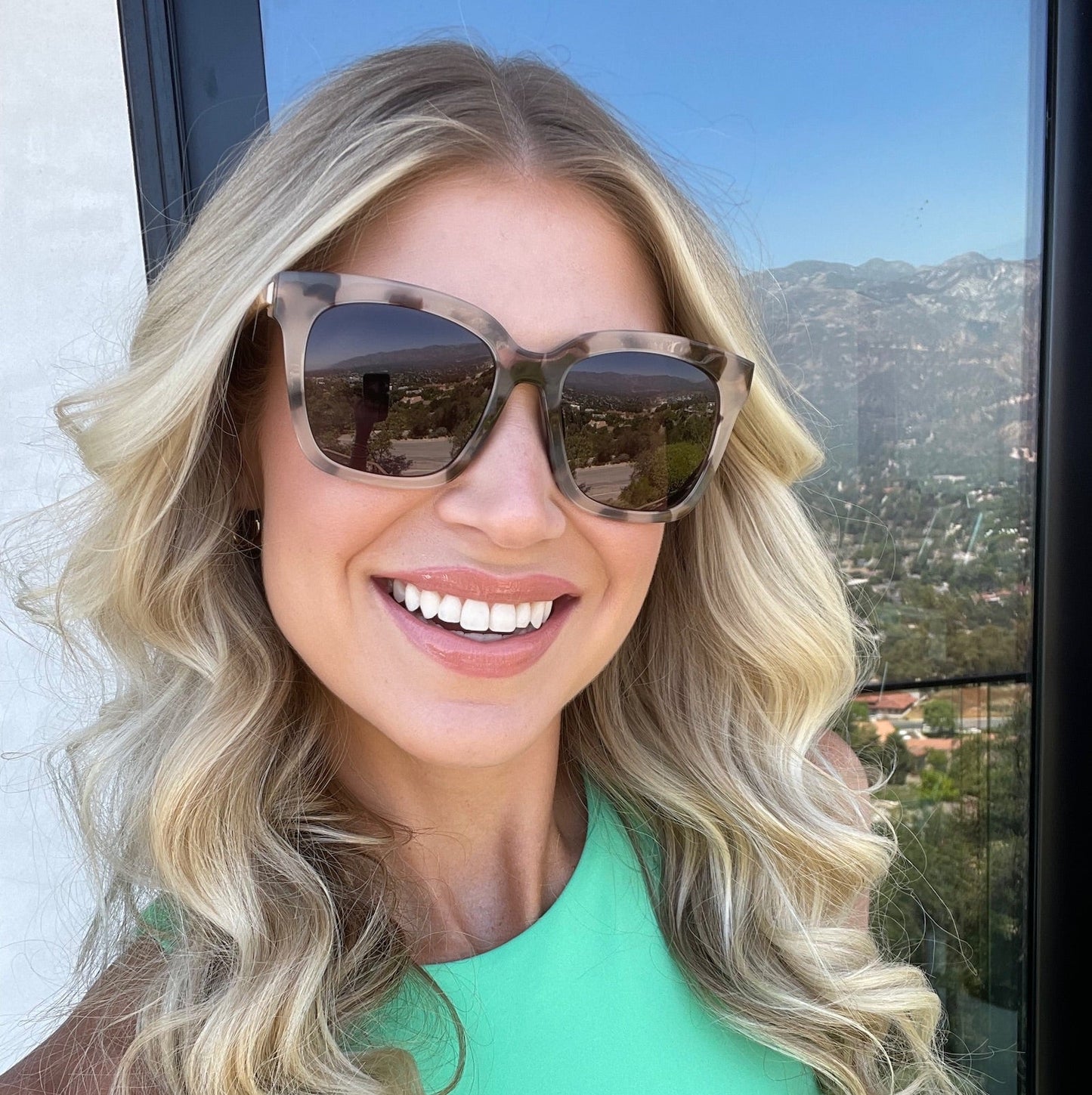 customer content - female with curly blonde hair smiling wearing diff eyewear bella square sunglasses with a cream tortoise frame and grey gradient polarized lenses