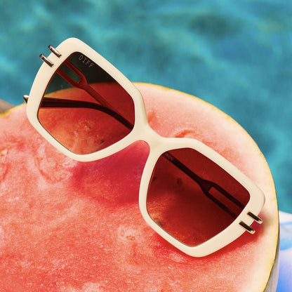 still life - diff eyewear featuring the dasha square sunglasses with a courtside ivory laying by a pool on a watermelon