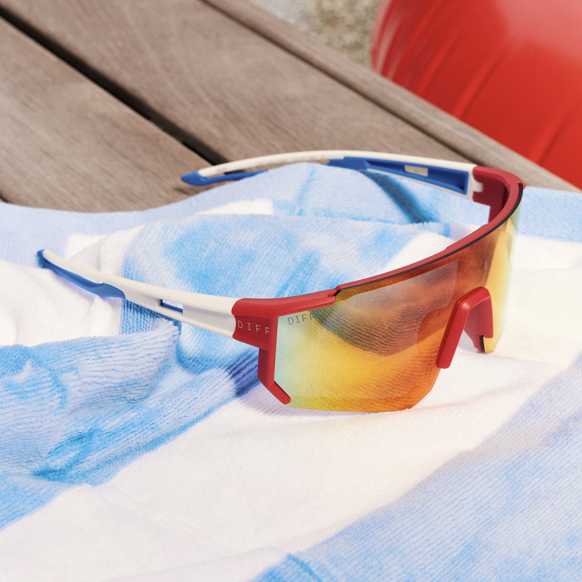 still life - diff sport featuring the heat shield sunglasses in firecracker red laying on a bench