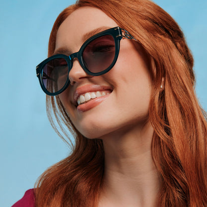 on model - female wearing frozen x diff eyewear featuring the anna cat eye sunglasses with a rich emerald frame and royal purple gradient lenses angled view