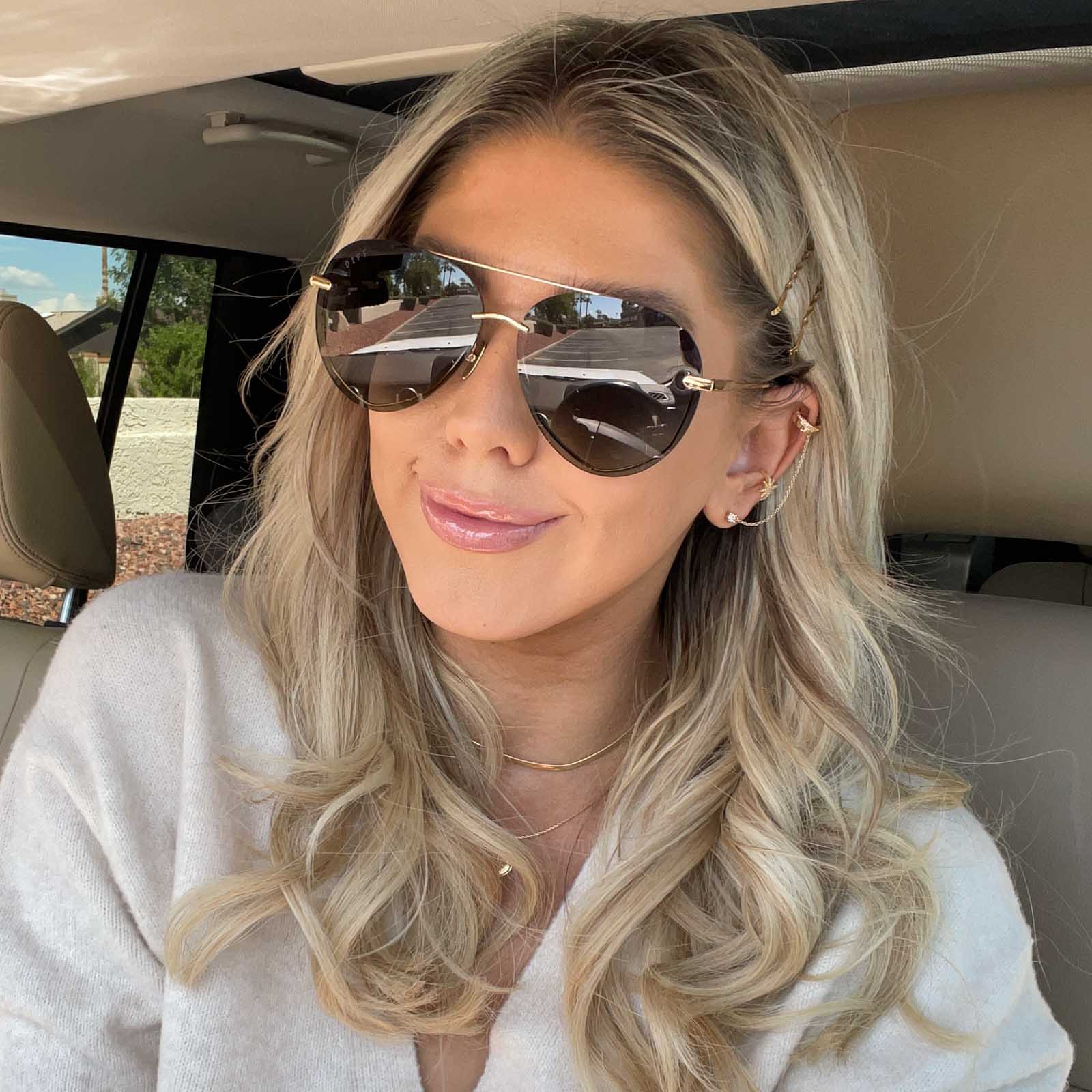 lifestyle - wink and a twirl wearing diff eyewear lenox aviator sunglasses with a gold, black metal frame and grey gradient polarized lenses