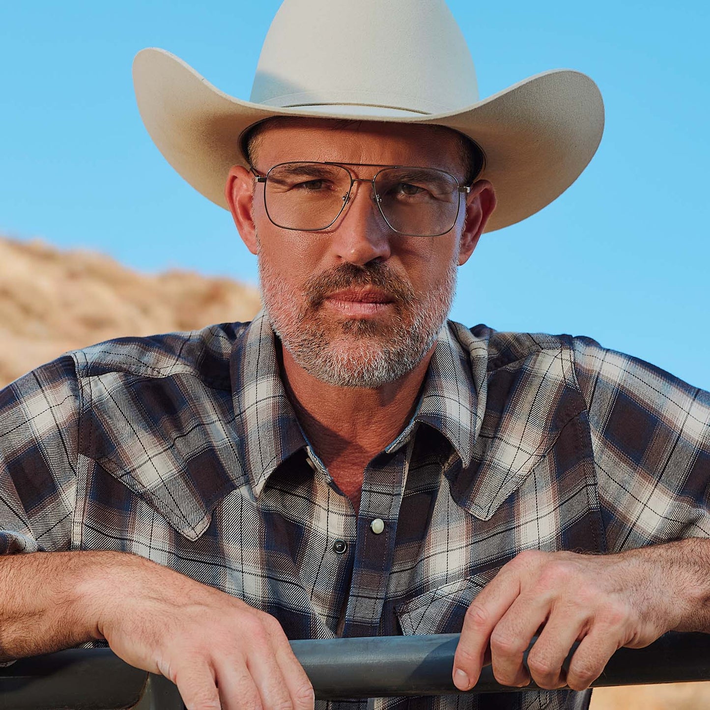 lifestyle - male at horse ranch wearing yellowstone x diff eyewear featuring the rip wheeler navigator prescription glasses with a silver frame front view