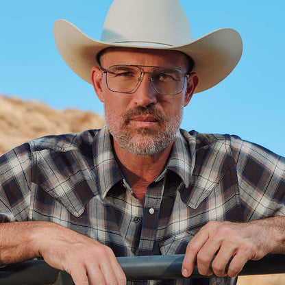 lifestyle - male at horse ranch wearing yellowstone x diff eyewear featuring the rip wheeler navigator prescription glasses with a silver frame front view