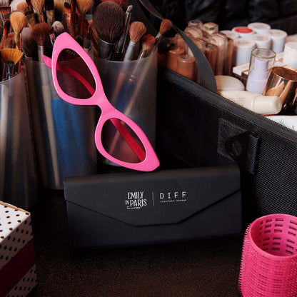 still life of emily in paris x diff eyewear featuring the emily 2.0 cateye sunglasses with a parisian pink frame and maracon pink lenses on makeup table