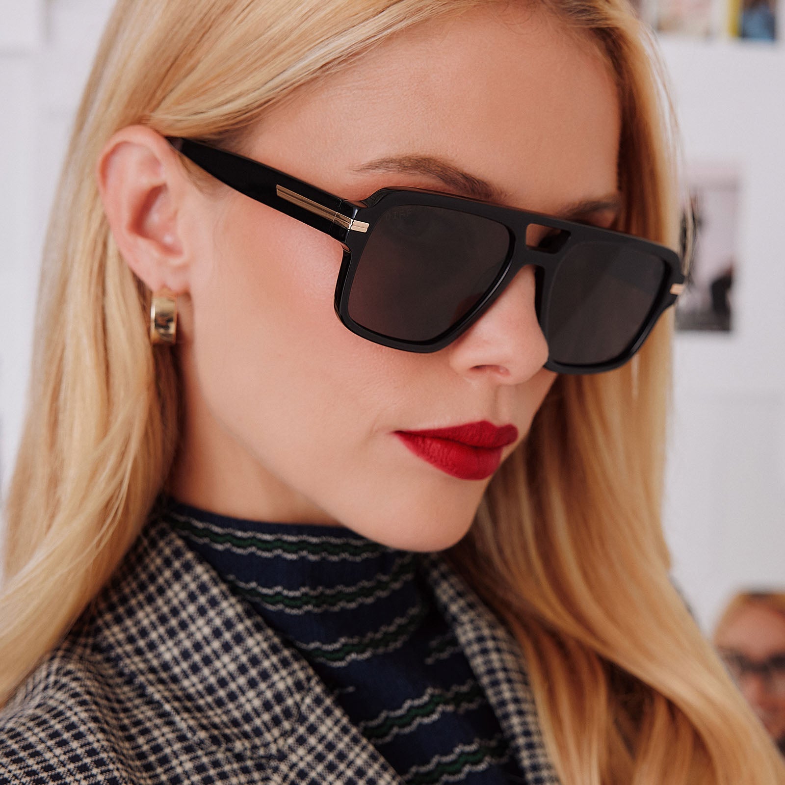 lifestyle - female in photo studio trying on emily in paris x diff eyewear featuring the julien navigator sunglasses with a jet noir black frame and smoke black lenses side view