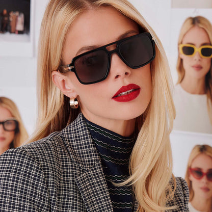 lifestyle - female in photo studio trying on emily in paris x diff eyewear featuring the julien navigator sunglasses with a jet noir black frame and smoke black lenses front view