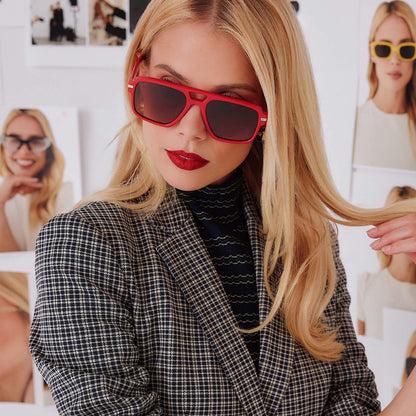 lifestyle - female in photo studio trying on emily in paris x diff eyewear featuring the julien navigator sunglasses with a rouge vogue red frame and warm brown gradient lenses front view